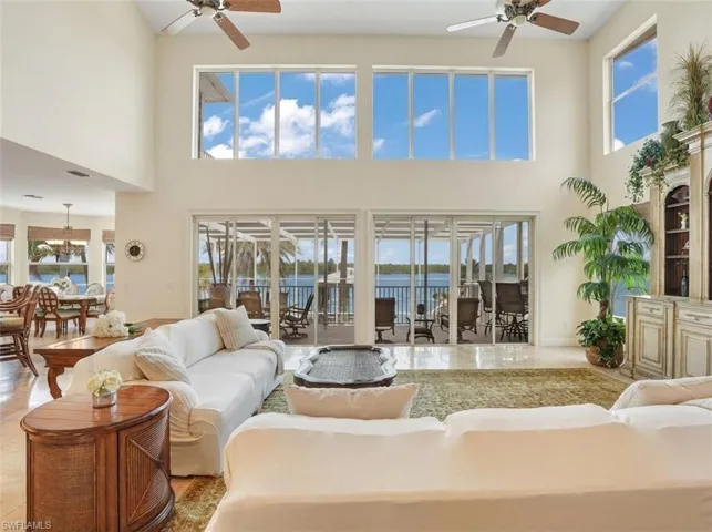 Living room with a ceiling fan, a water view, a high ceiling, and suspended lighting - Virtually Edited Image