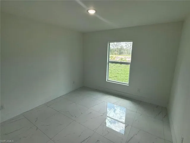 Spare room featuring baseboards and light marble finish flooring