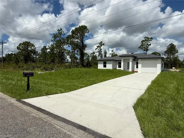 Prairie-style house featuring an attached garage, concrete driveway, a front lawn, and stucco siding