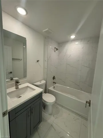Bathroom with shower / bath combination, vanity, light marble finish flooring, and recessed lighting
