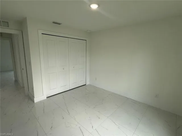 Unfurnished bedroom featuring light marble finish floors and a closet