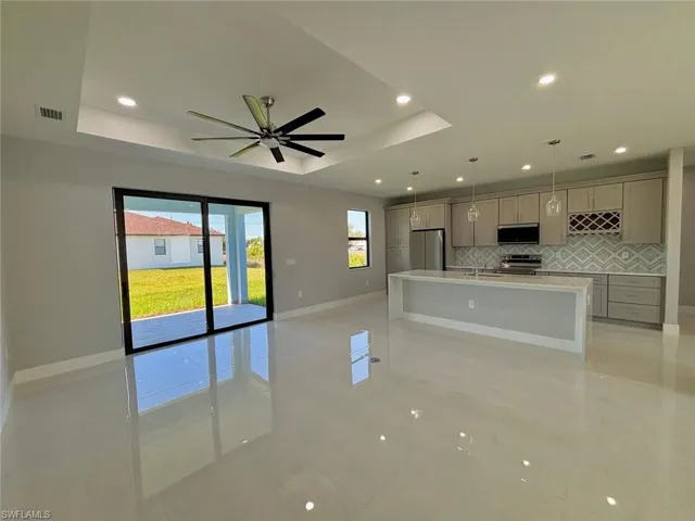 Kitchen featuring gray cabinets, visible vents, a tray ceiling, decorative backsplash, and stainless steel appliances