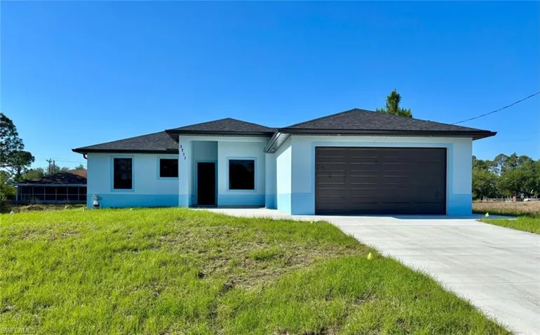 Prairie-style home with a garage, driveway, stucco siding, and a front lawn