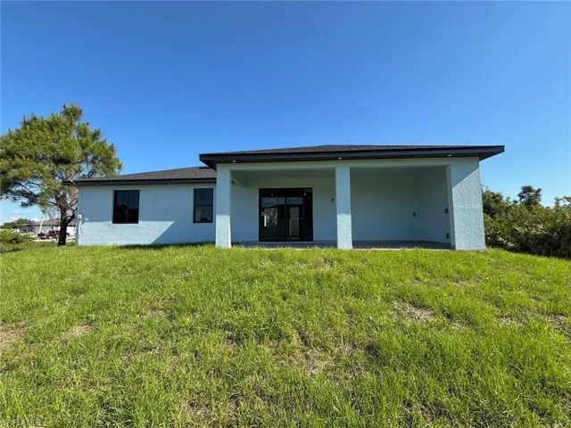 Back of property featuring stucco siding and a lawn