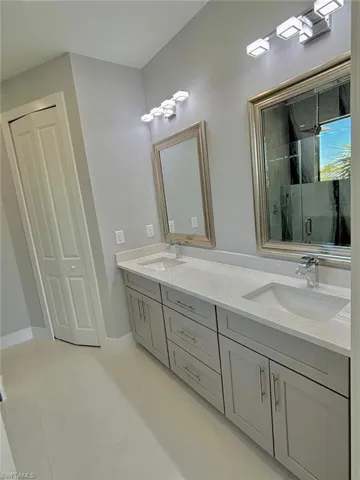 Full bathroom with a sink, tile patterned flooring, a marble finish shower, and double vanity