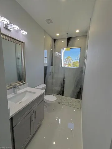 Bathroom featuring vanity, visible vents, recessed lighting, toilet, and a marble finish shower