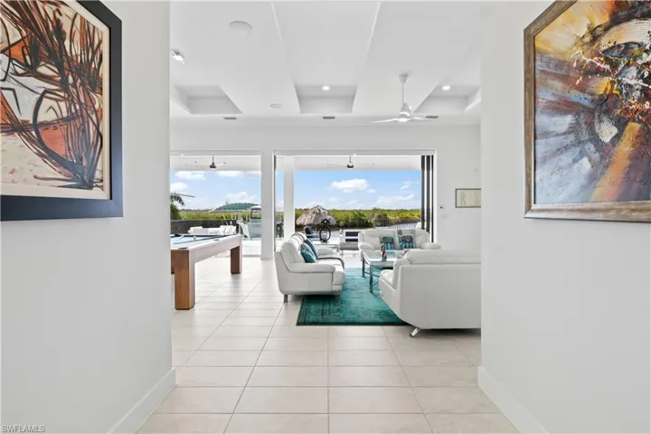 An inviting foyer with soaring ceilings and lighted tray ceilings - the back wall is literally a disappearing dual slider wall that blends the indoors and outdoors.  Kevlar automatic screens are another upgrade as well as Lutron powered automatic shades!