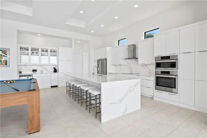 View of the kitchen with the additional entertainment area which includes a stand alone icemaker.  Behind those two large cabinets is a large walk in pantry!