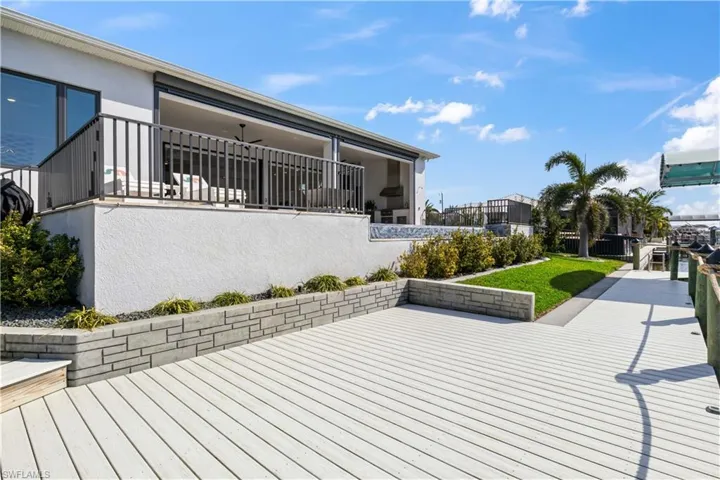 Outdoor living space with grass area and fencing as well as beautiful lush landscaping, flowerbeds and curbing.