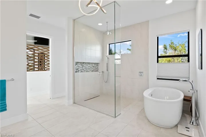 A beautiful soaking tub and large shower with rainhead and wall to ceiling glass frame.