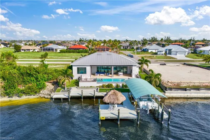 View from the water - extensive outdoor living - both around the pool and on the dock.  14,000 pound boat lift, wrap around dock with tiki hut and plenty of room to expand.