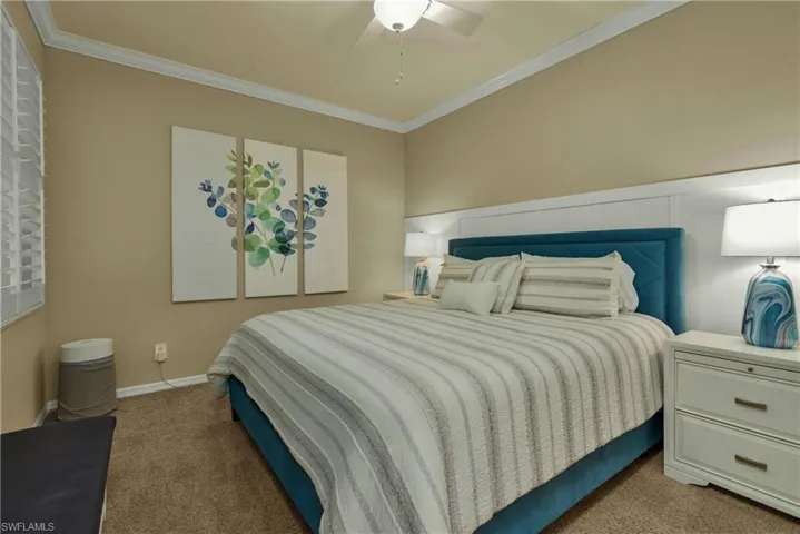 Bedroom featuring ornamental molding, light colored carpet, and ceiling fan