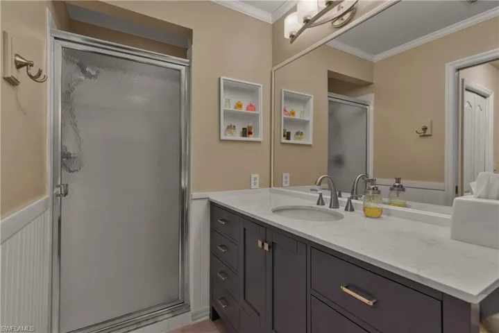 Bathroom featuring crown molding, vanity, and an enclosed shower