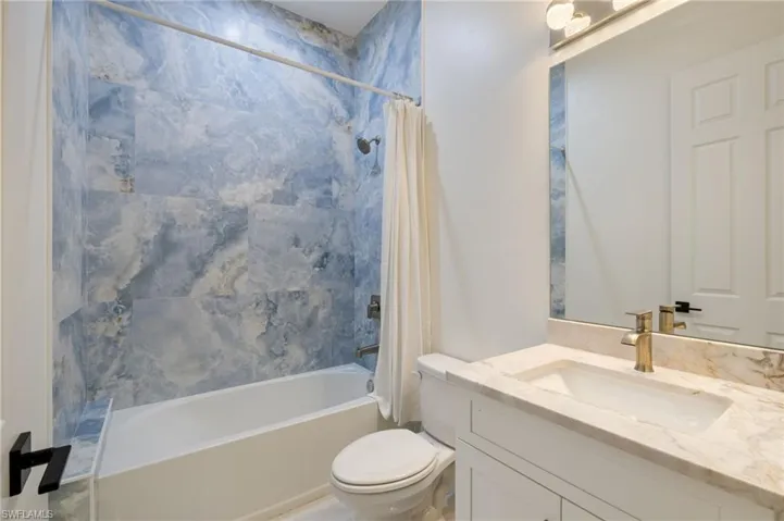 Bedroom featuring light marble finish flooring, connected bathroom, and ceiling fan