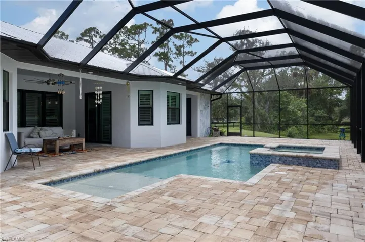View of pool featuring a patio area, a sunroom, a lanai, and a pool with connected hot tub