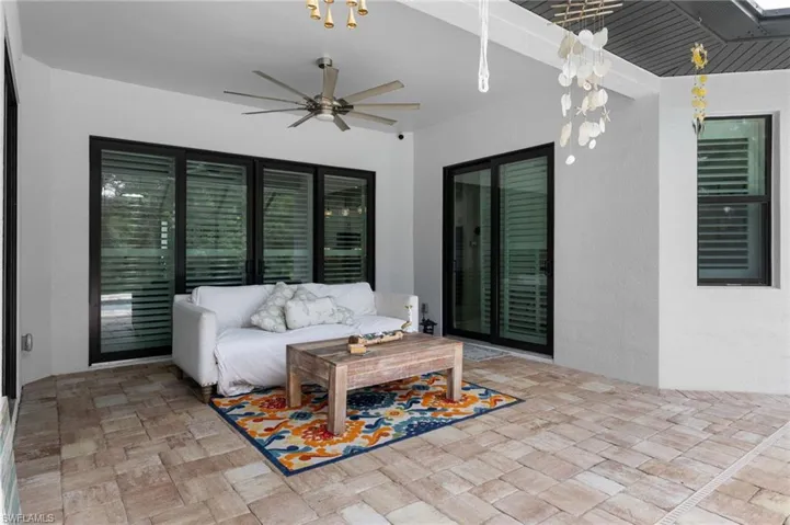 View of pool featuring a sunroom, a pool with connected hot tub, a patio area, and glass enclosure