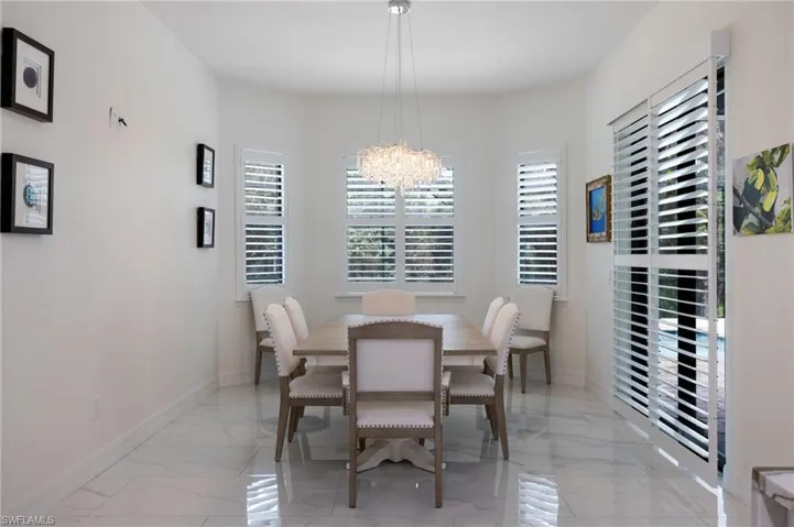 Kitchen featuring light marble finish flooring, white cabinets, light stone counters, decorative backsplash, and decorative light fixtures
