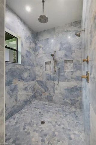 Bedroom with light marble finish floors, ceiling fan, and ensuite bathroom