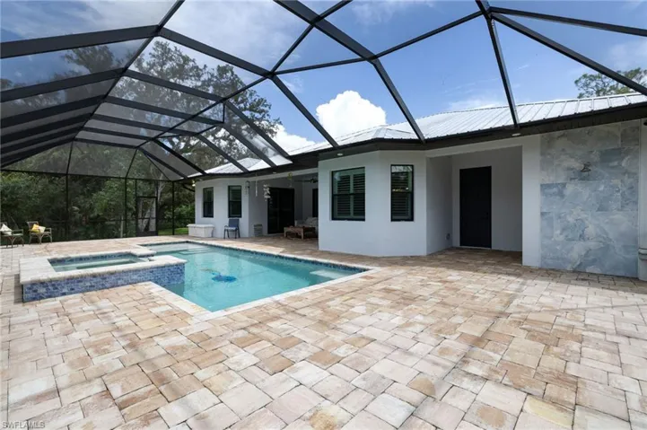 View of pool featuring a sunroom, a ceiling fan, a patio area, a pool with connected hot tub, and glass enclosure