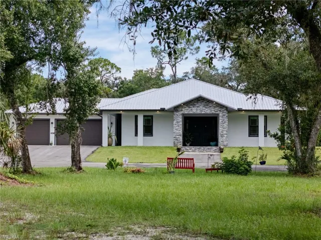 View of front of house with asphalt driveway, an attached garage, a front yard, and covered porch