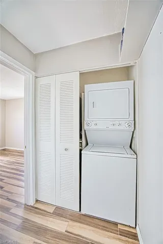 Laundry area with light wood-style flooring and stacked washer and dryer