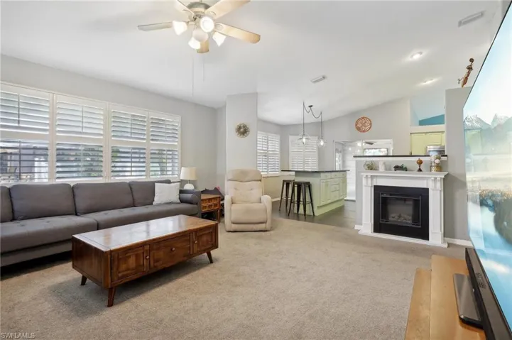 Carpeted living room with lofted ceiling and ceiling fan