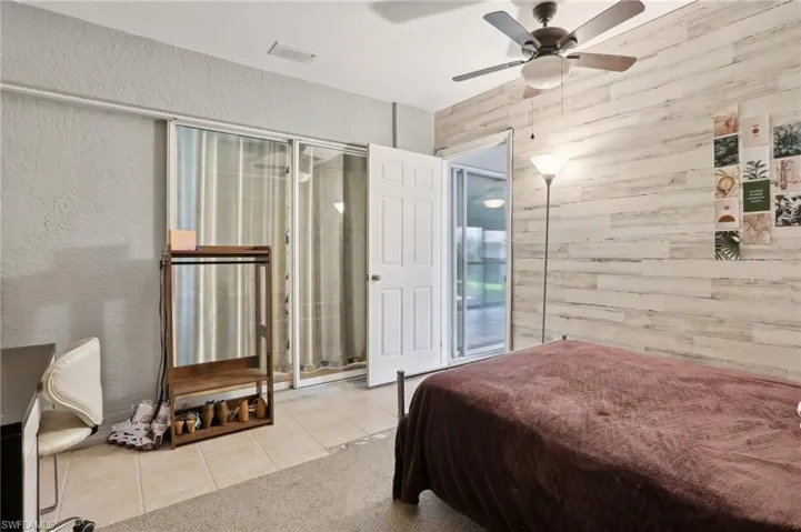 Tiled bedroom featuring wood walls and ceiling fan