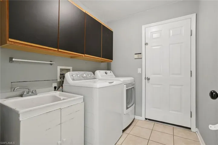 Laundry area featuring light tile patterned floors, independent washer and dryer, and cabinets