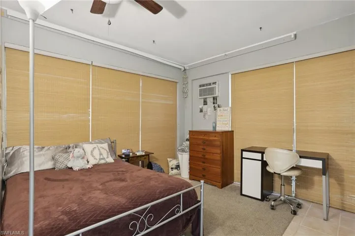 Tiled bedroom with a wall unit AC, ceiling fan, and a closet