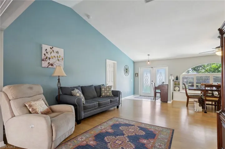 Living room with french doors, high vaulted ceiling, light wood-type flooring, and ceiling fan