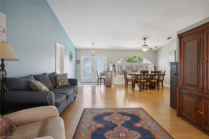 Living room featuring lofted ceiling, french doors, light hardwood / wood-style flooring, and ceiling fan