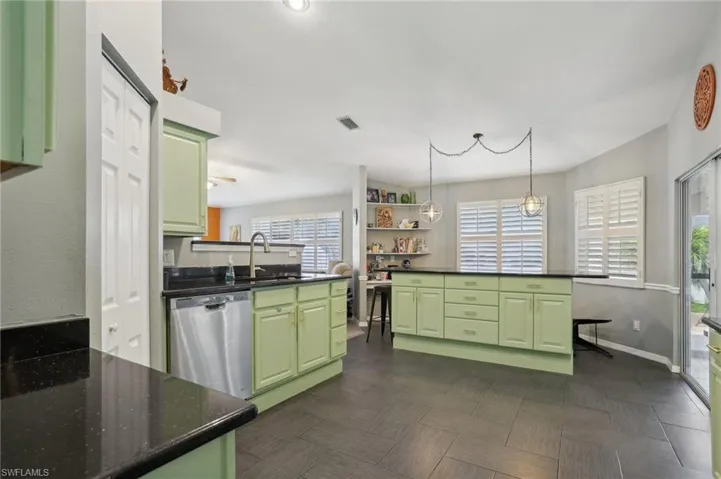 Kitchen featuring a healthy amount of sunlight, stainless steel dishwasher, dark parquet flooring, and green cabinetry