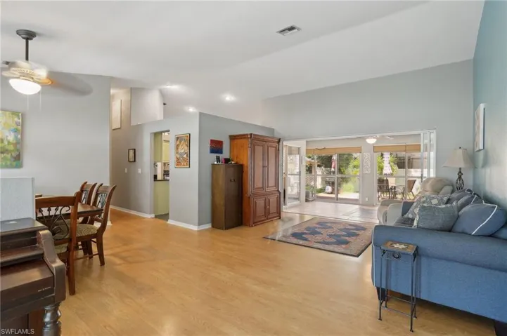Living room with light hardwood / wood-style floors, ceiling fan, and vaulted ceiling