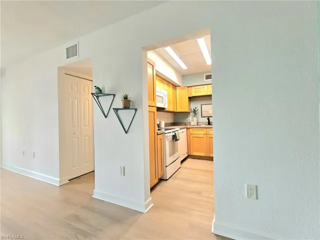 Kitchen featuring light wood-type flooring, white appliances, light countertops, and light brown cabinets