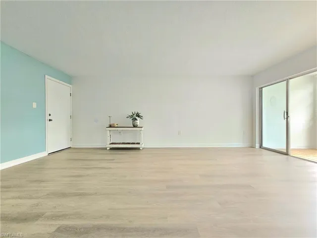Unfurnished living room featuring light wood finished floors and baseboards