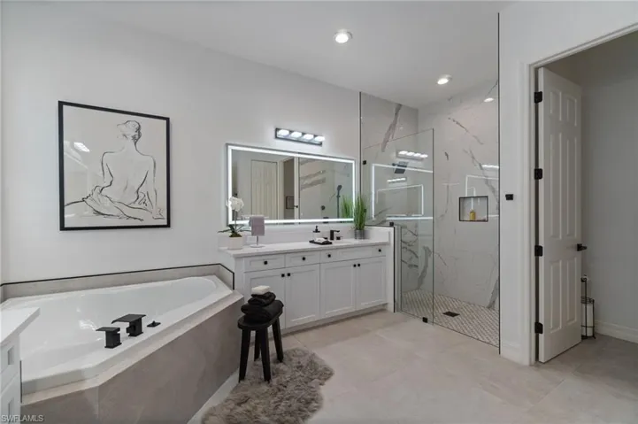 Full bath with dual quartz vanity, large format floor to ceiling shower enclosure with frameless glass, a separate tiled corner soaking tub…. All with abundant vanity and recessed lighting, and contrasted with high contrast matte black hardware.