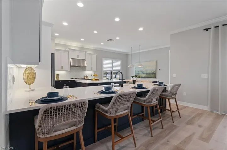 Upgraded modern coastal Kitchen reimagined with contrasting navy lower cabinets, stainless appliance package including gas range cooktop, crown molding, a timeless backsplash, crisp white quartz countertops, 2nd island prep sink … all set off with golden hardware, fixtures and faucets.