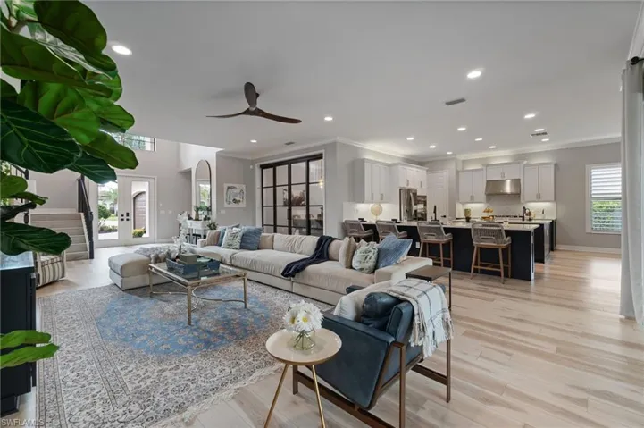 Living room with a ceiling fan, crown molding, recessed lighting, and light wood finished floors