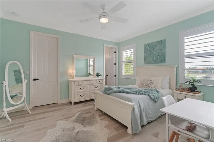 Bedroom with crown molding, light wood-style floors, and a ceiling fan