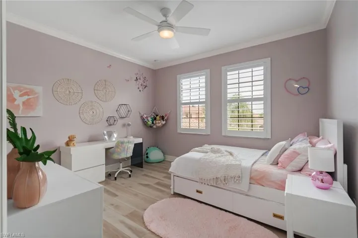 1 of 3 upstairs Bedrooms featuring light wood-style flooring, ornamental crown molding, a loom for a student desk or vanity, and a modern ceiling fan - all with a morning sunrise exposure.