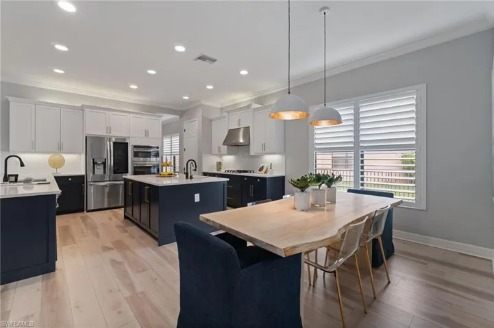 Kitchen with crown molding, an island with sink, appliances with stainless steel finishes, light countertops, and decorative backsplash