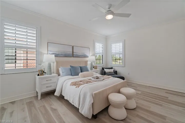Bedroom with crown molding, light wood finished floors, and a ceiling fan