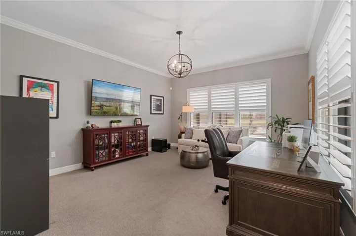 Bright executive private home office with a pool and lake view.  It features crown molding, a decorative chandelier, and large safe.