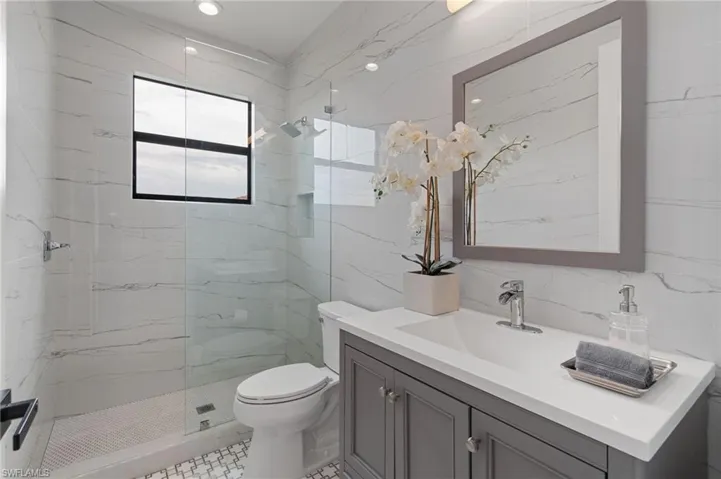 Designer upgraded upstairs hall Bathroom adorned w/ exquisite tile mosaics, custom grey vanity, and large format stone look floor to ceiling tile surround and upgraded full tile walls.