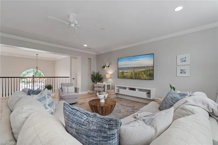 Living room featuring wood finished floors, a ceiling fan, crown molding, recessed lighting, and a chandelier