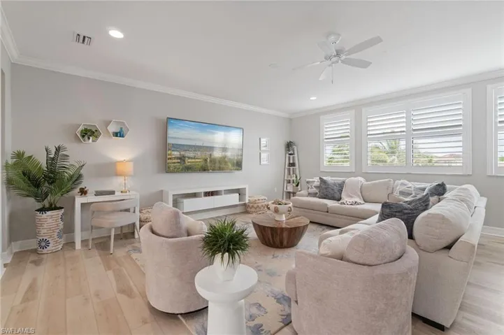 Living room featuring light wood-style flooring, ornamental molding, ceiling fan, and recessed lighting