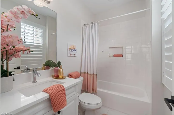 Bathroom featuring vanity and shower / bathtub combination with curtain