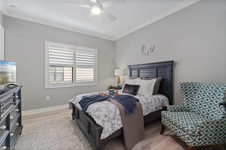 Bedroom featuring ornamental molding, wood finished floors, and a ceiling fan