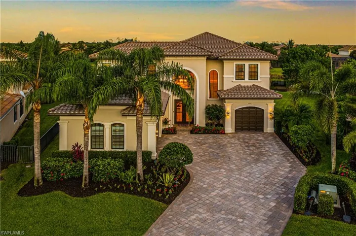 Mediterranean / spanish-style 2 story elevation  featuring decorative paver driveway, neutral stucco siding, rich contrasting garage and trim and a curved tile roof.