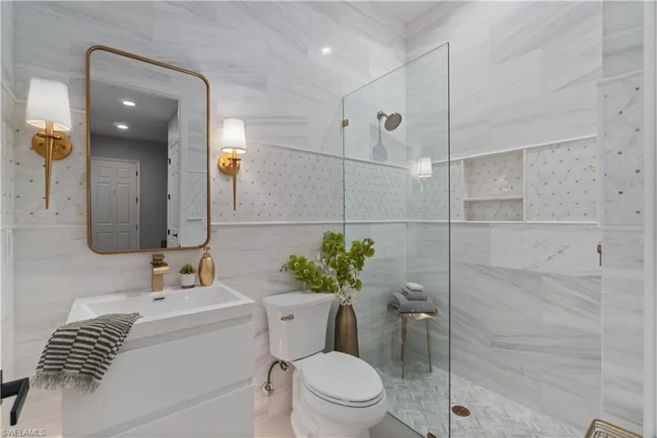 Every inch of this downstairs full bathroom is lavishly upgraded with full marble tile including marble crown molding to coordinate!  The intricate high end mosaic decorative accents with pops of beautiful brass metal highlight details and hardware.  Stunning frameless open glass enclosure. Custom floating vanity.  Adjacent to downstairs guest bedroom.
